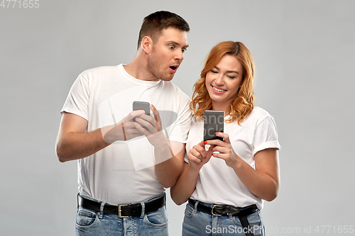 Image of happy couple in white t-shirts with smartphones