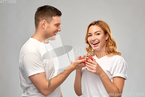 Image of happy couple in white t-shirts with christmas gift