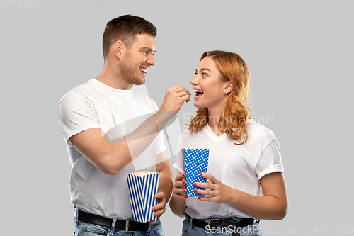 Image of happy couple in white t-shirts eating popcorn