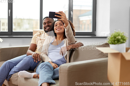 Image of happy couple moving to new home and taking selfie
