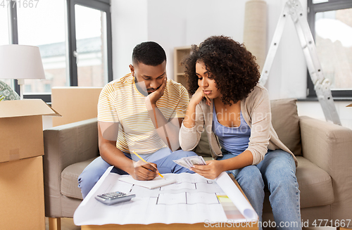 Image of sad couple with blueprint counting money at home