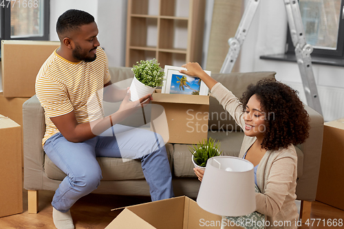 Image of happy couple packing boxes and moving to new home