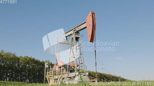 Image of Operating oil and gas well in oil field, profiled against the blue sky