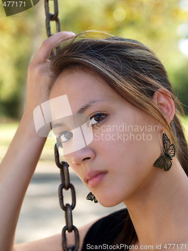 Image of Young asian american woman holding chain from swing