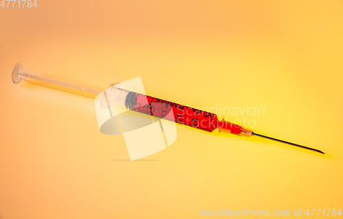 Image of Syringe with blood on orange background