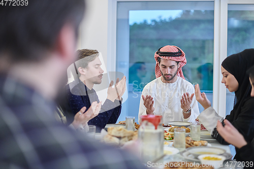 Image of Muslim family making iftar dua to break fasting during Ramadan.