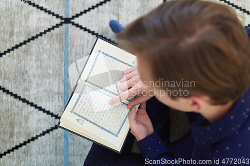 Image of Young muslim man reading Quran during Ramadan