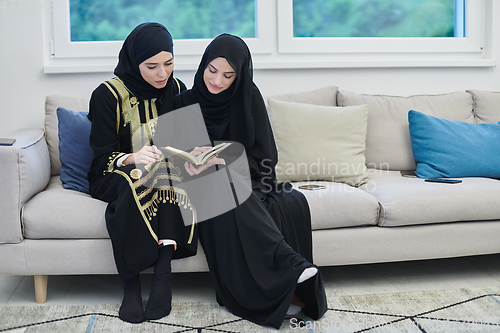 Image of Portrait of young muslim women reading Quran in modern home.