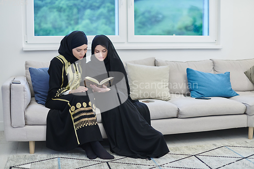 Image of Portrait of young muslim women reading Quran in modern home.