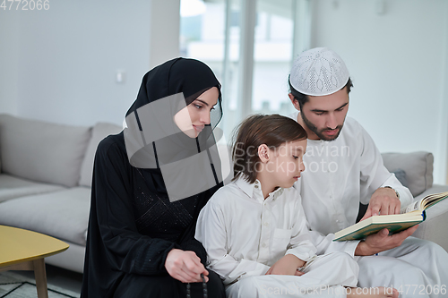 Image of Young muslim family reading Quran during Ramadan