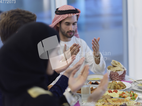 Image of Muslim family making iftar dua to break fasting during Ramadan