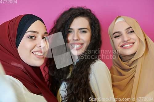 Image of Muslim women taking selfie by mobile phone isolated on pink background