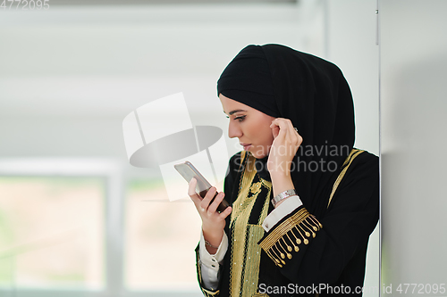 Image of Portrait of Arab woman in traditional clothes using mobile phone