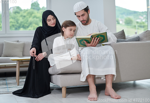 Image of Young muslim family reading Quran during Ramadan