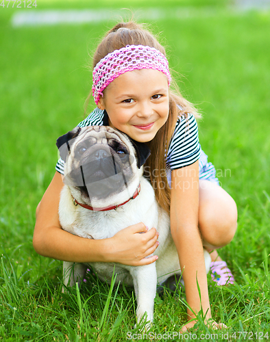 Image of Little girl and her pug dog on green grass