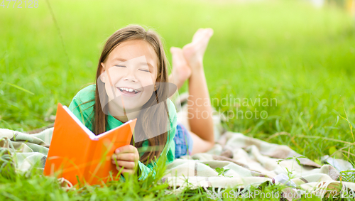 Image of Little girl is reading a book outdoors