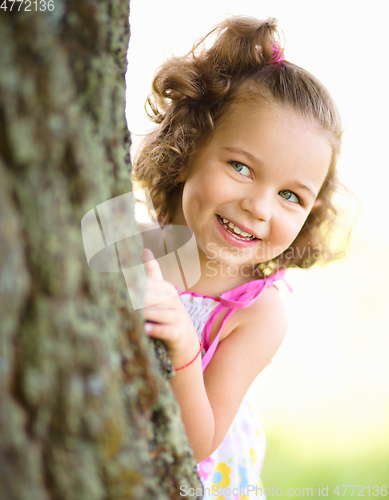 Image of Cute little girl is playing hide and seek