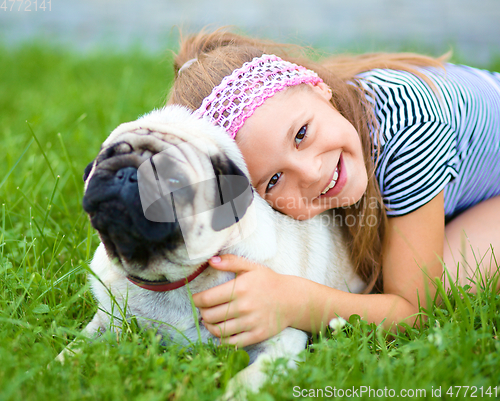 Image of Little girl and her pug dog on green grass