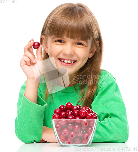 Image of Cute girl is eating cherries