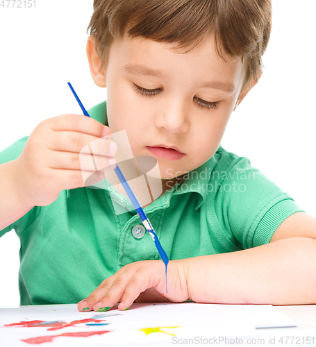 Image of Little boy is playing with paints