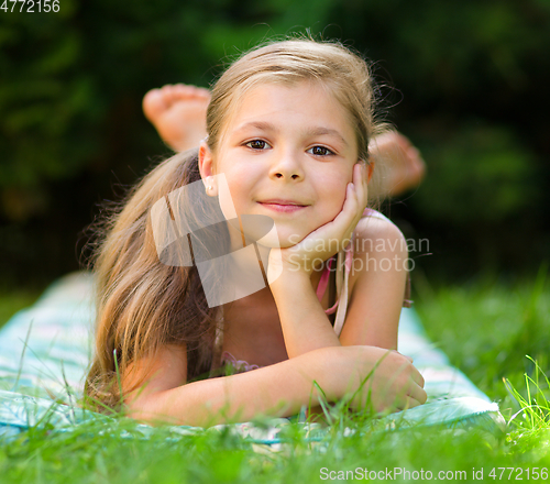 Image of Portrait of a little girl laying on green grass