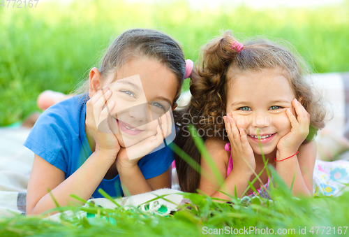 Image of Two little girls are laying on green grass