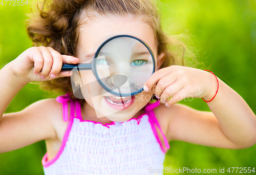 Image of Little girl is looking through magnifier