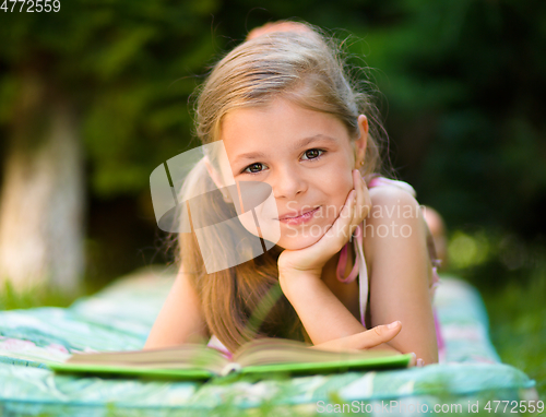 Image of Little girl is reading a book outdoors