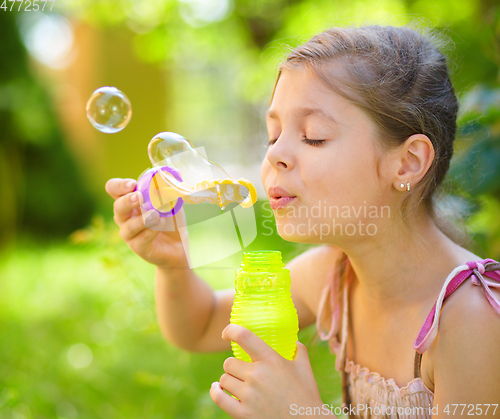 Image of Little girl is blowing a soap bubbles