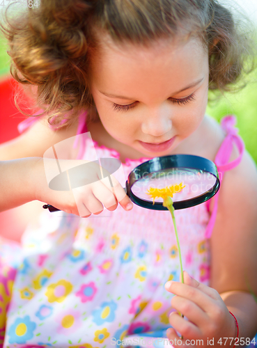 Image of Young girl is looking at flower through magnifier