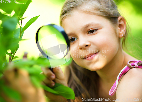 Image of Girl is looking at tree leaves through magnifier