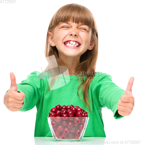Image of Cute girl is eating cherries showing thumb up sigh