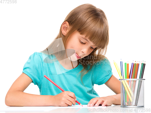 Image of Little girl is drawing using pencils