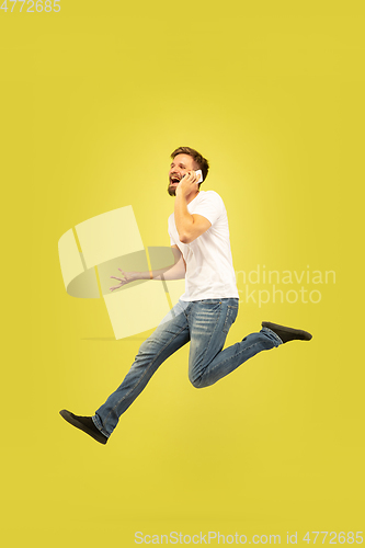 Image of Full length portrait of happy jumping man on yellow background