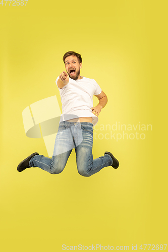 Image of Full length portrait of happy jumping man on yellow background