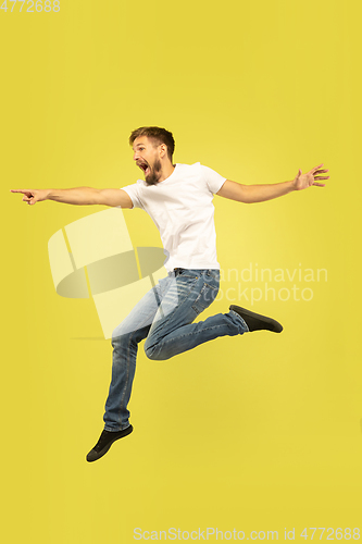 Image of Full length portrait of happy jumping man on yellow background