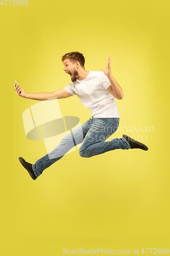 Image of Full length portrait of happy jumping man on yellow background