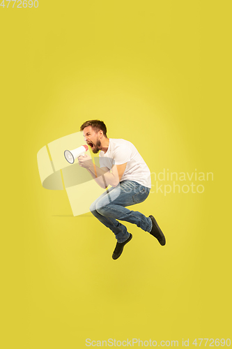 Image of Full length portrait of happy jumping man on yellow background