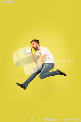 Image of Full length portrait of happy jumping man on yellow background