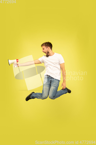 Image of Full length portrait of happy jumping man on yellow background