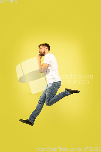 Image of Full length portrait of happy jumping man on yellow background