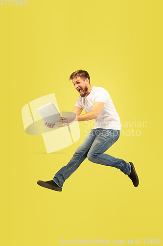 Image of Full length portrait of happy jumping man on yellow background