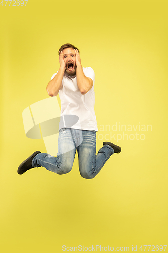 Image of Full length portrait of happy jumping man on yellow background