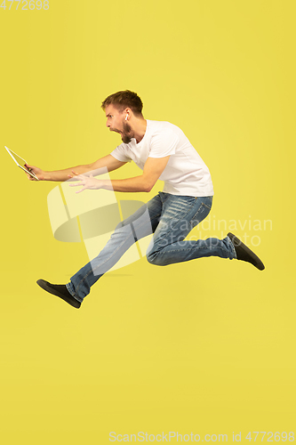 Image of Full length portrait of happy jumping man on yellow background