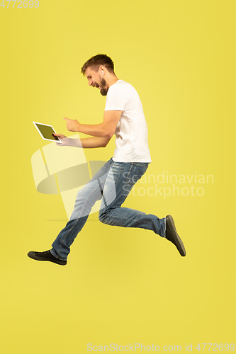 Image of Full length portrait of happy jumping man on yellow background