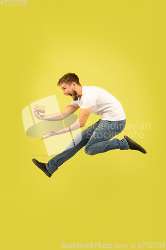 Image of Full length portrait of happy jumping man on yellow background