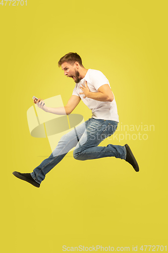 Image of Full length portrait of happy jumping man on yellow background