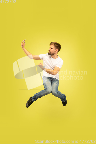 Image of Full length portrait of happy jumping man on yellow background