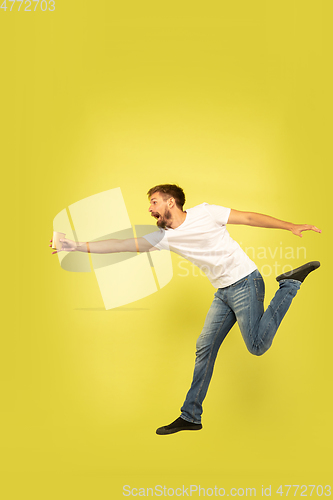 Image of Full length portrait of happy jumping man on yellow background