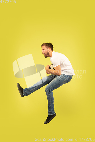 Image of Full length portrait of happy jumping man on yellow background